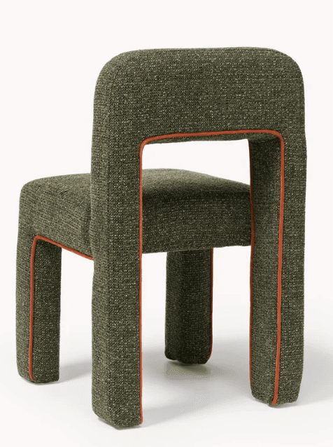 A fully upholstered armless dining chair featuring a unique rounded, chunky silhouette. The entire frame, including the back and legs, is seamlessly covered in a textural dark green tweed or bouclé-like fabric. A striking orange piping outlines all edges of the chair, providing a vibrant contrast to the main green upholstery. The backrest is open between the seat and the top, creating a negative space that defines the chair's structure. The legs are thick and integrated into the overall padded form. — 3D model