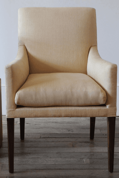 A fabric-upholstered armchair with a gently curved backrest and integrated armrests. The chair features four dark wooden legs, with the rear legs exhibiting a slight curve. The upholstery appears to be a textured woven fabric. — 3D model