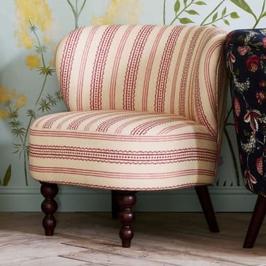 A fully upholstered accent chair with a curved back and seat. The chair features a cream-colored fabric with a repeating pattern of thin red stripes and a more intricate red geometric pattern interspersed with the stripes. It is supported by four legs, with the front two legs having a turned, bulbous design and the rear legs being tapered and darker in color. The overall design suggests a vintage or traditional aesthetic. — 3D model