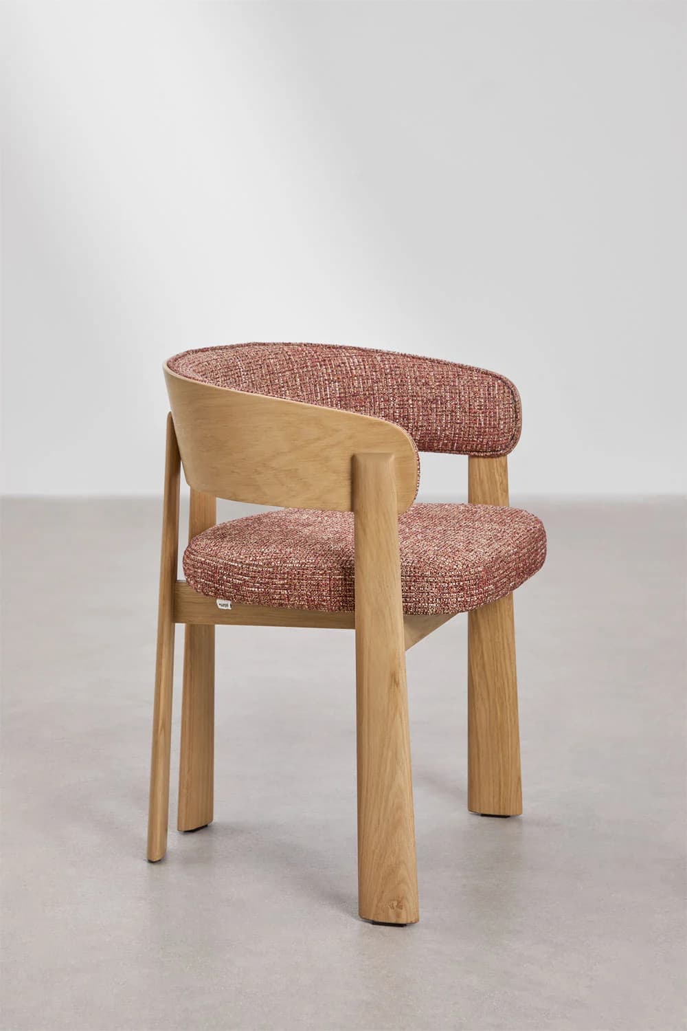 A modern dining armchair featuring a solid light oak wood frame with a curved backrest and upholstered seat and back in a textured, multi-tonal red/rust fabric. The chair has integrated armrests formed by the bentwood back and thick, tapering wooden legs. The design emphasizes natural materials and smooth, contemporary lines. — 3D model