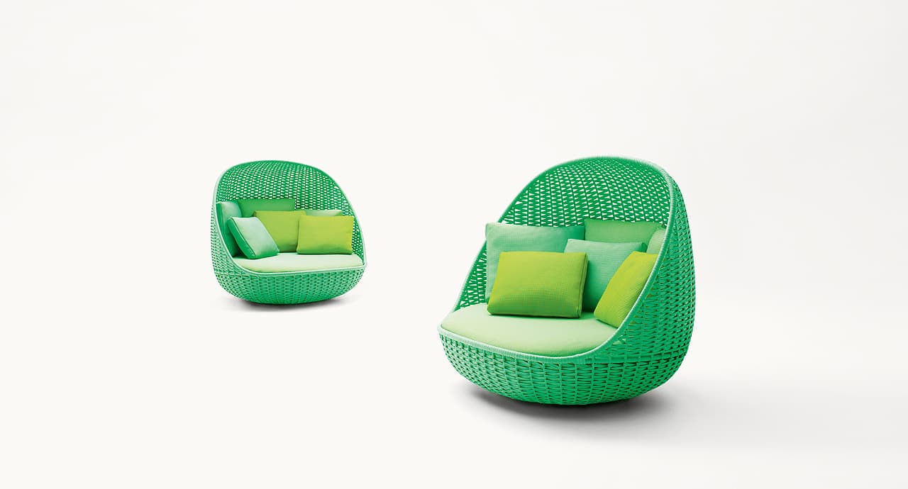 A vibrant green, pod-shaped lounge chair featuring a finely woven synthetic exterior and multiple cushions in varying shades of green, designed for outdoor use. — 3D model