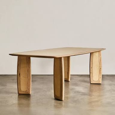 A rectangular dining table crafted from light-colored plywood, featuring a smooth tabletop with gently rounded corners and thick, curved slab-like legs that display the layered construction of the wood. — 3D model