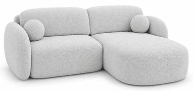 An L-shaped contemporary sectional sofa featuring soft, rounded contours and upholstered in a light, textured fabric, accompanied by two spherical accent cushions. — 3D model