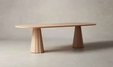 An oval-shaped dining table with a light wood finish. The tabletop is relatively thin with rounded edges. It is supported by two conical bases, each featuring a fluted or segmented design, tapering from a wider base to a narrower top where they connect to the underside of the tabletop. The bases appear to be made of solid wood. — 3D model