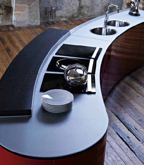 A modern, curved kitchen island featuring a rich wood veneer base and a light grey solid surface or laminate countertop. The island is equipped with three integrated black ceramic cooktops, two stainless steel circular sinks, and a single gooseneck faucet. The design is sleek and contemporary, with a minimalist aesthetic and functional integration of kitchen appliances. — 3D model