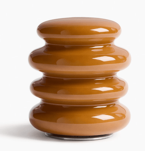 A compact, glossy caramel-colored object with a stacked, segmented, cylindrical form, resting on a slim metallic base. — 3D model
