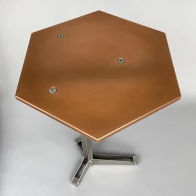 A hexagonal side table with a copper-colored top and a brushed metal pedestal base. The top is secured to the base with three visible screws. The base has a modern, geometric design with three legs splayed outwards from a central column. — 3D model