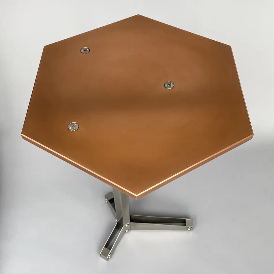 A hexagonal side table with a copper-colored top and a brushed metal pedestal base. The top is secured to the base with three visible screws. The base has a modern, geometric design with three legs splayed outwards from a central column. — 3D model