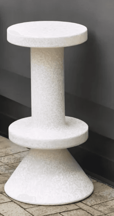 A modern, monochromatic, speckled stool or accent table featuring a cylindrical central column, a circular flat top, a wider circular transition piece, and a conical flared base, all in a uniform light-colored composite material. — 3D model
