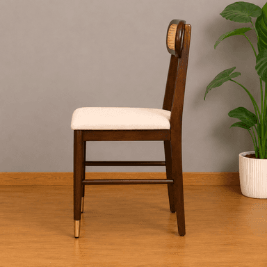 A contemporary dining chair featuring a dark stained wooden frame, a distinctive oval-shaped backrest with natural cane webbing, and a light beige upholstered seat. The chair's tapered legs are accented with brass ferrules on the front two feet. — 3D model