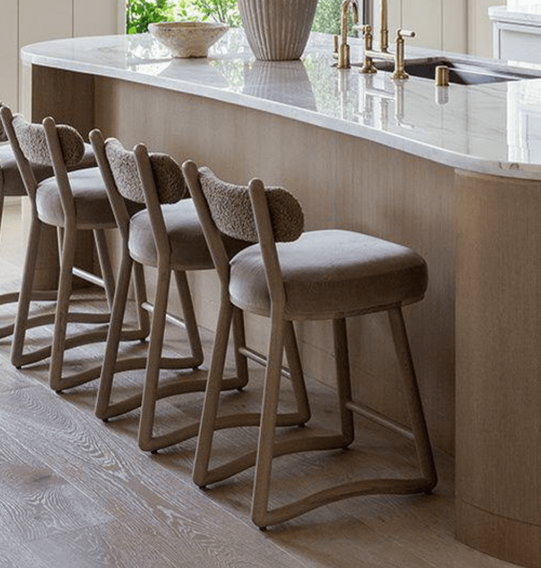A contemporary bar stool featuring a light wooden frame with a circular upholstered seat and a distinctive curved bouclé backrest. The stool has four tapered legs connected by a rectangular footrest. — 3D model