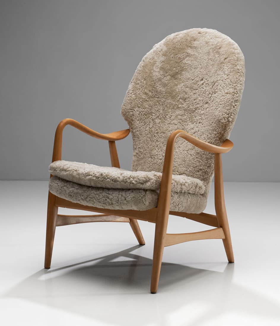 A high-backed armchair with a wooden frame and plush sheepskin upholstery. The frame consists of curved wooden arms and legs. The seat and back are fully upholstered in a textured, cream-colored sheepskin material, giving it a soft and inviting appearance. The design suggests a focus on comfort and organic forms. — 3D model