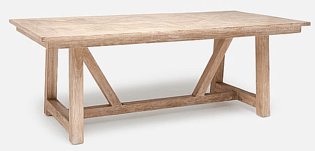 A rectangular dining table with a light, distressed wood finish. The tabletop features a planked construction with a subtle chevron pattern. The base consists of two substantial A-frame style legs connected by a horizontal stretcher, with additional diagonal bracing elements within the A-frames. The overall aesthetic suggests a rustic or farmhouse style. — 3D model