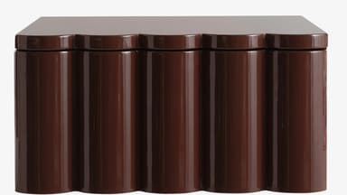 A brown cabinet with a high-gloss finish. The front features a scalloped design with vertical, rounded panels. The top surface is flat and extends slightly beyond the main body. — 3D model