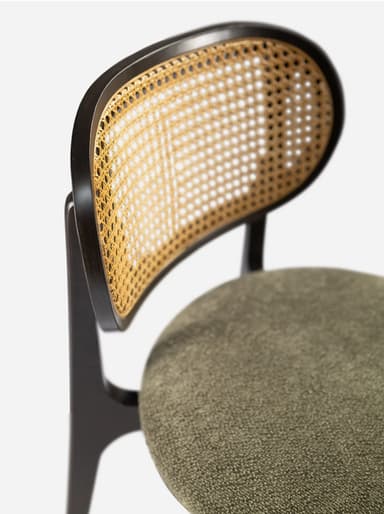 A modern side chair featuring a dark wooden frame with a distinctive curved backrest. The backrest incorporates a woven cane panel. The seat is upholstered in a textured, neutral-toned fabric. The legs are tapered and angled outwards, contributing to a sleek silhouette. — 3D model