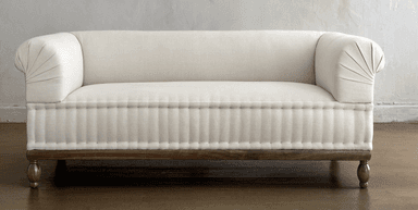 A cream-colored upholstered daybed with a rolled armrest and a tufted lower section. The daybed is supported by a dark wooden frame and features turned wooden legs. — 3D model