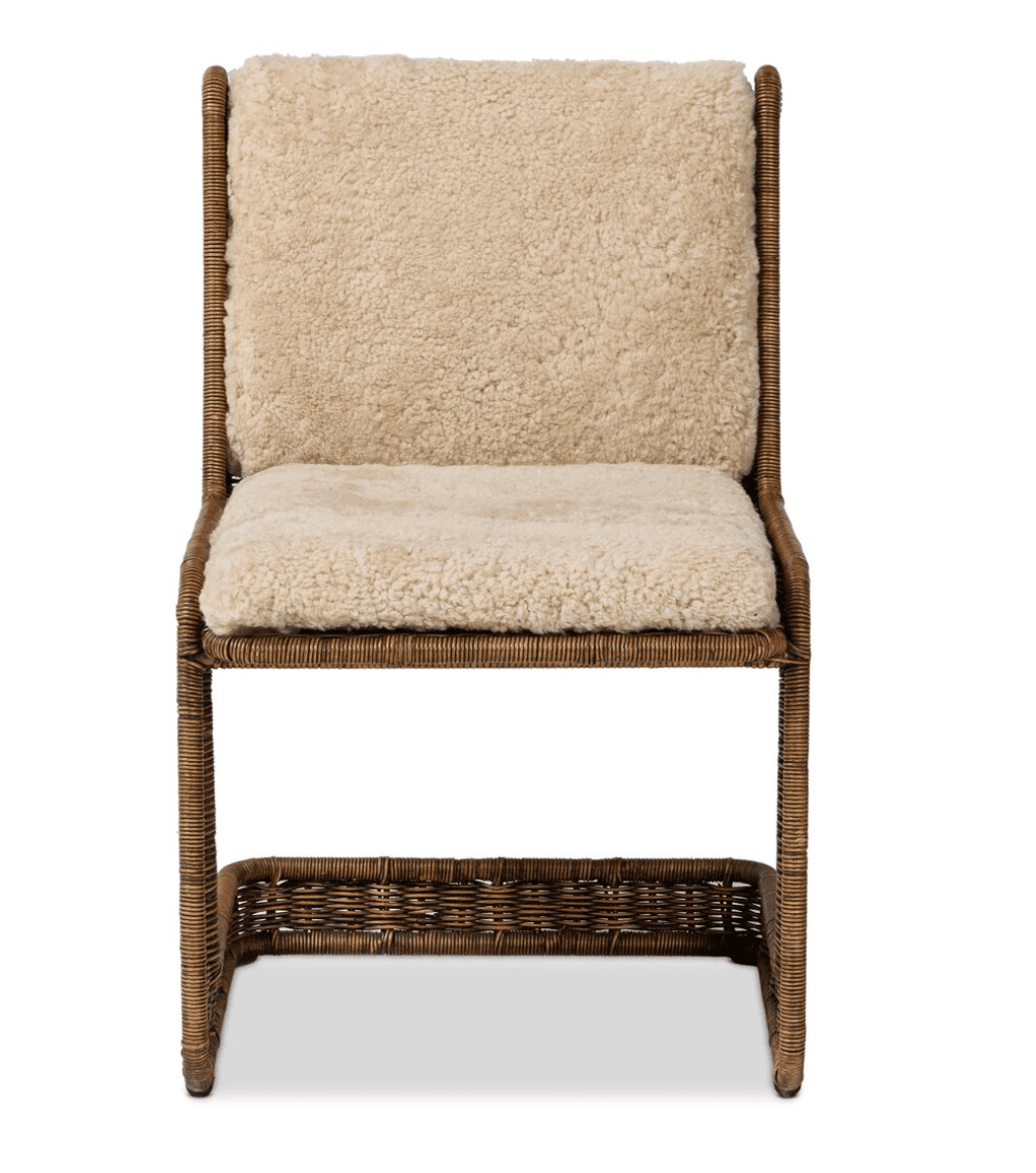 A chair with a rattan or wicker frame and upholstered seat and backrest with a sheepskin or faux sheepskin material. The frame has a woven texture. It features a low shelf or footrest integrated into the base, also constructed from woven material. — 3D model