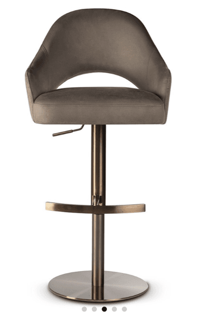 A contemporary bar stool featuring a taupe or light gray upholstered seat and back with integrated armrests and a distinctive cutout design. It stands on a bronze-finished metal pedestal base with a circular footrest and includes a lever for height adjustment. — 3D model