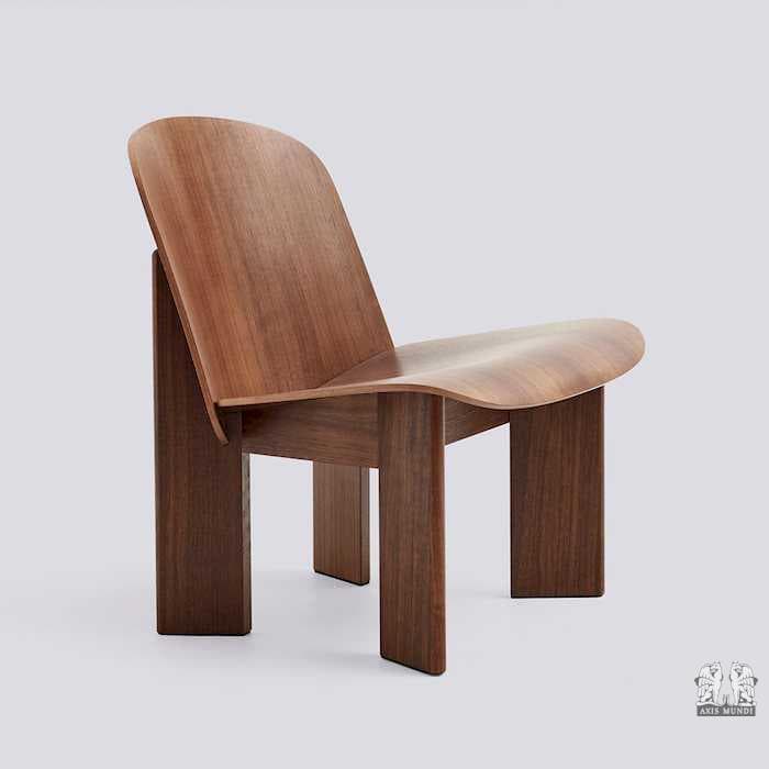A modern lounge chair constructed from bent plywood and solid wood. The chair features a gently curved backrest that flows into a contoured seat. It is supported by four substantial, block-like legs with chamfered edges. The overall design is minimalist with a focus on organic forms and material texture. — 3D model
