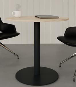 A modern round table featuring a light wood grain top and a sturdy black metal pedestal base. The tabletop is smooth with visible wood grain patterns. The base consists of a cylindrical central column connected to a wide, flat circular disc, both finished in matte black. The design is minimalist and contemporary. — 3D model