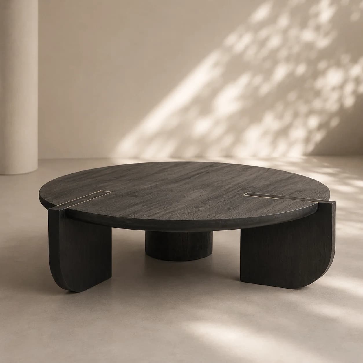 A contemporary round coffee table featuring a dark, possibly ebony-stained wood finish with visible grain. The tabletop is circular and incorporates four thin, rectangular brass inlays arranged symmetrically around the center. The base consists of multiple thick, architectural legs that combine curved and straight elements, providing stable support and contributing to the table's modern aesthetic. — 3D model