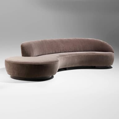A modern, curvilinear sectional sofa upholstered in a luxurious brownish-grey (taupe) velvet fabric. It features a continuous, gently curved backrest and an integrated, circular chaise lounge element at one end. The sofa rests on a discreet, recessed dark base, giving it a low-profile and floating appearance. — 3D model