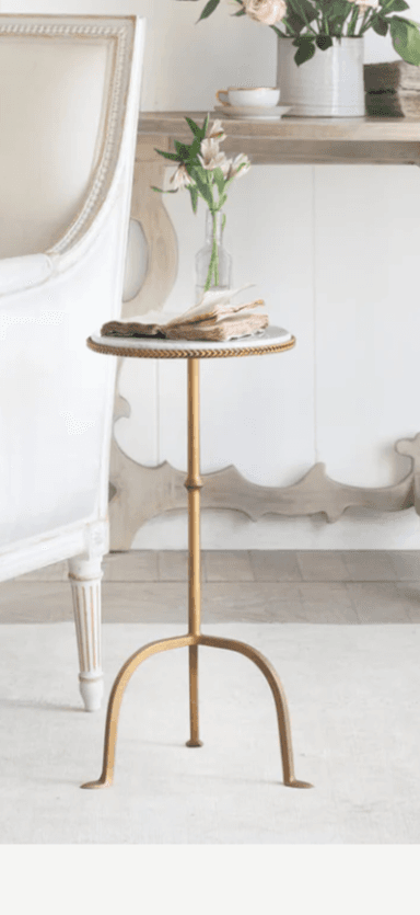 A round side table with a white marble top and a gold-finished metal base. The base has a slender, adjustable central column and three gracefully curved legs that splay outwards. The edge of the marble top is accented with a decorative braided trim. — 3D model