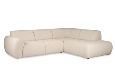 An L-shaped contemporary sectional sofa upholstered in a light cream bouclé fabric. The sofa features a long three-seat section combined with an integrated chaise lounge on the right, providing ample seating. Its design is characterized by soft, rounded edges on the arms and back, and a low-profile silhouette with minimalist dark feet. The cushions appear integrated, creating a seamless and inviting aesthetic. — 3D model