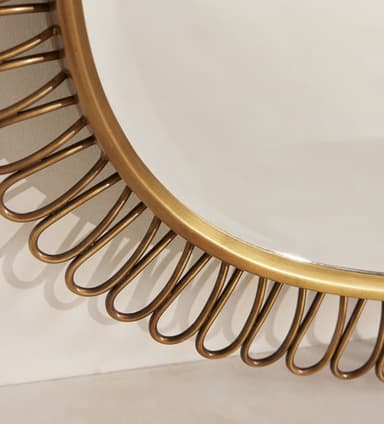 A vintage wall mirror featuring a rounded rectangular glass surface surrounded by a distinctive looped brass or metallic frame. The individual loops form a continuous, decorative border around the main reflective surface, casting subtle shadows on the wall. — 3D model