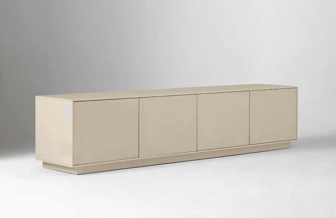 A long, low-profile contemporary sideboard cabinet featuring four handleless doors, finished in a light greige lacquer. The unit rests on a subtly recessed plinth base, giving it a floating appearance. Its minimalist design emphasizes clean lines and a smooth, uninterrupted facade. — 3D model