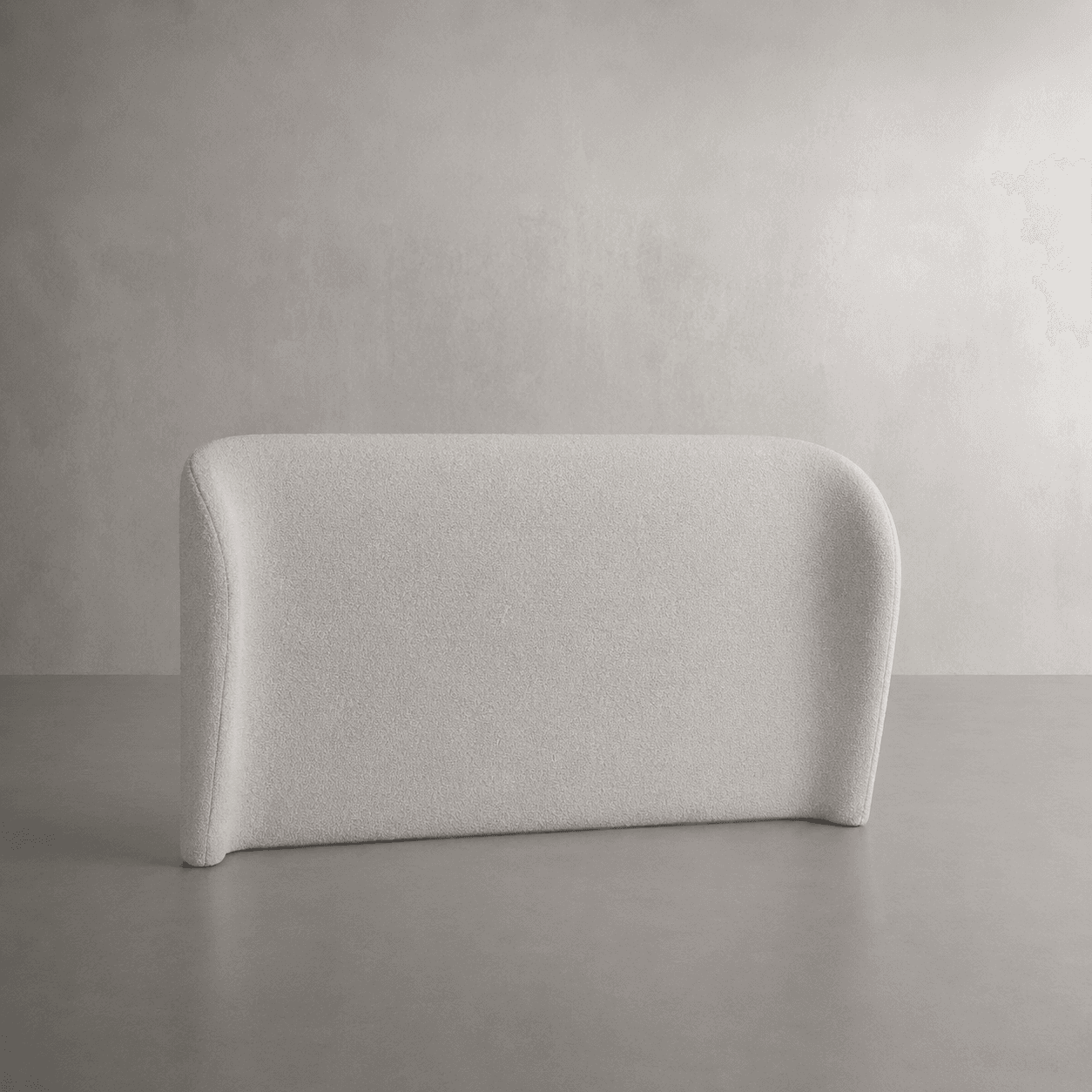 A minimalist, rectangular upholstered panel designed to function as a headboard. It features gently rounded corners at the top and a slight curvature on the side edges, giving it a soft, contemporary aesthetic. The panel is covered in a light beige, textured fabric, likely boucle or a similar woven material, providing a plush, inviting surface. — 3D model