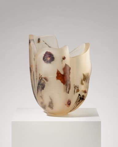 An irregular, organic-shaped vase crafted from translucent resin with various dried botanicals, including leaves, flowers, and stems, embedded within its walls. The resin exhibits a yellowish-amber hue and a matte, frosted finish. The top rim is uneven and undulating, contributing to its sculptural quality. — 3D model
