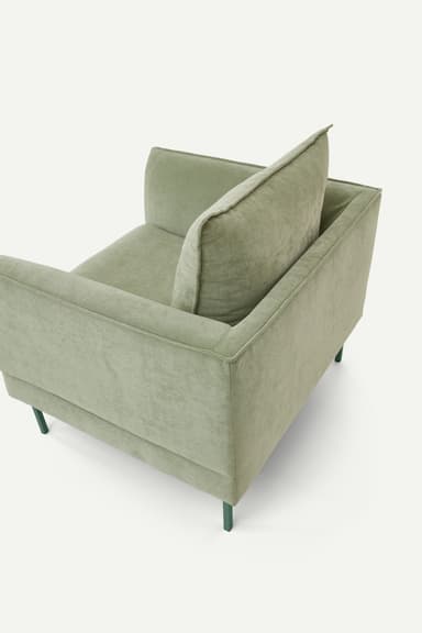 A contemporary upholstered armchair featuring a soft, muted sage green fabric, loose seat and back cushions, and slender, complementary dark green metal legs. — 3D model