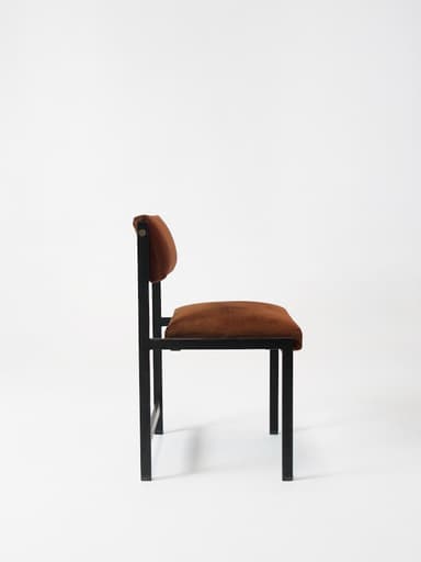 A minimalist accent chair with a dark metal frame and upholstered seat and backrest. The frame has a simple, geometric construction with straight lines. The seat and backrest are covered in a rich, brown velvet-like fabric. — 3D model