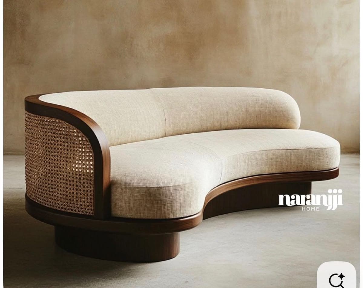 A contemporary curved sofa featuring a light, neutral fabric upholstery, a dark-stained solid wood frame, and a distinctive cane webbing detail on one side of the backrest. The sofa rests on a dark wooden plinth base, giving it a substantial and grounded appearance without visible legs. Its flowing, curvilinear form is designed for multi-person seating. — 3D model