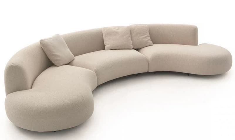 A large, curved sectional sofa with a rounded, organic shape. The sofa features a textured fabric upholstery and includes several loose throw pillows for added comfort. Its modular design suggests it can be configured in various arrangements. — 3D model