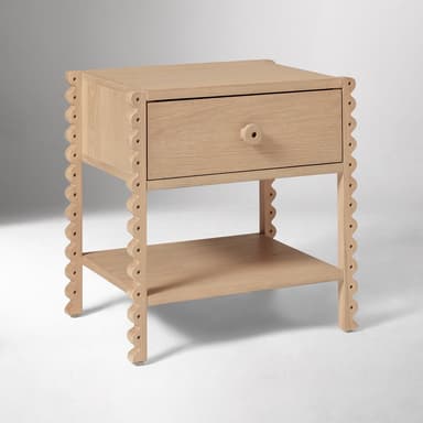 A light-toned wooden nightstand featuring a single drawer and an open lower shelf, distinguished by decorative scalloped edges on its vertical frame. — 3D model
