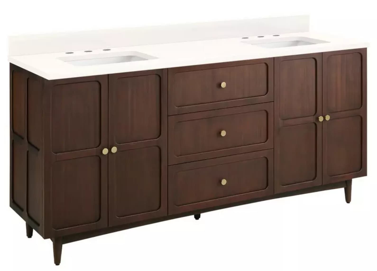 A double vanity unit with a white countertop featuring two integrated sinks and faucets. The base unit is constructed from dark stained wood, featuring three central drawers with brass knobs and two cabinet doors on either side, also with brass knobs. The unit is supported by four tapered legs, indicative of a mid-century modern or transitional style. The design incorporates recessed paneling on the cabinet doors and drawer fronts. — 3D model