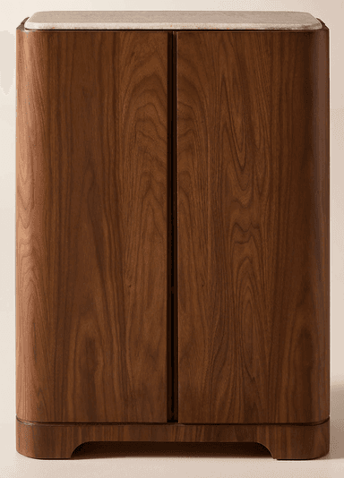 A tall, narrow storage cabinet featuring a rich dark wood finish, likely walnut, with elegantly rounded corners. The top surface is adorned with a light-colored, possibly beige or cream, marble slab. The front facade indicates two full-height doors, suggesting ample interior storage. The cabinet stands on a subtle, recessed plinth base. — 3D model
