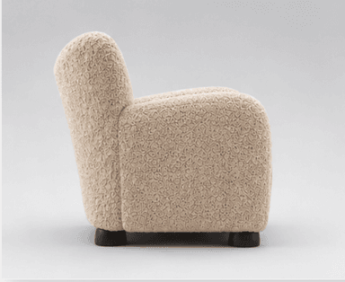 A modern upholstered armchair featuring a distinctive highly textured, beige fabric and a rounded, inviting silhouette, set on small, dark wooden feet. — 3D model