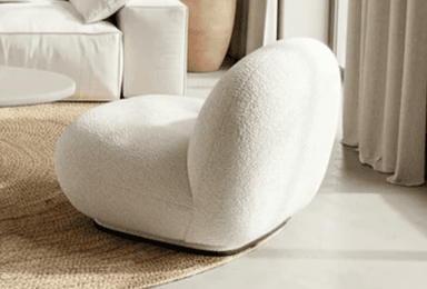 An armless lounge chair upholstered in a cream-colored boucle fabric, featuring a rounded, organic silhouette and a low profile base. — 3D model