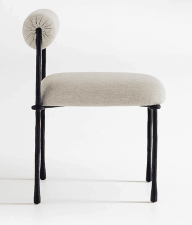 A modern armless chair featuring a dark-colored metal frame with an organic, somewhat irregular texture. It has a light beige or off-white upholstered seat cushion and a cylindrical, bolster-style backrest, also upholstered in the same fabric. The chair stands on four slender, tapered legs. — 3D model