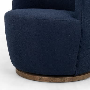A contemporary armchair upholstered in a textured navy blue fabric. It features a rounded back and integrated armrests that curve gently downwards. The chair is supported by a circular, dark wood swivel base, allowing for 360-degree rotation. The upholstery has a boucle or similar textured finish. — 3D model