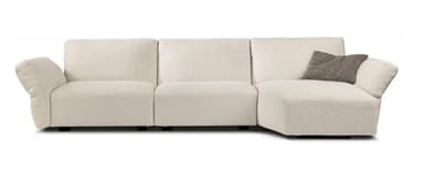 An L-shaped sectional sofa upholstered in a textured bouclé fabric, featuring a long, integrated chaise lounge section. The sofa has a contemporary design with soft, rounded edges, wide armrests, and plush, inviting cushions. Its off-white color and low profile suggest a modern and comfortable aesthetic. — 3D model