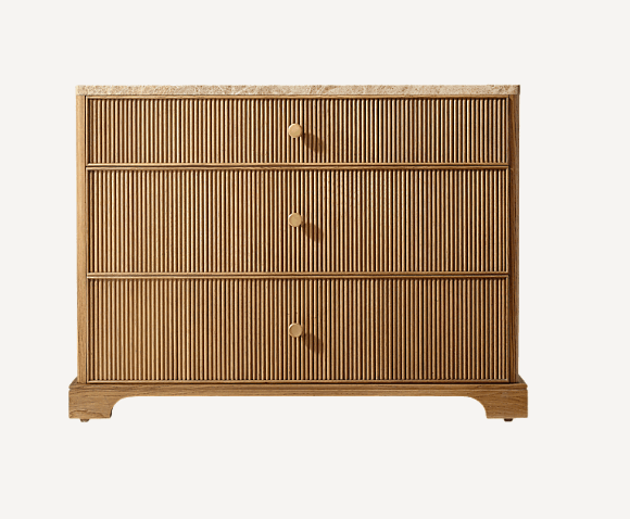 A modern chest of drawers featuring three full-width drawers with reeded fronts, a beige marble top, and small circular brass pulls. The frame is made of light-toned wood and it stands on a recessed plinth base. — 3D model