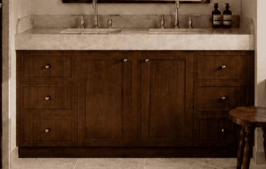 A contemporary double sink bathroom vanity featuring a dark brown wooden cabinet, a light beige stone countertop, two integrated undermount sinks, and brushed nickel faucets and hardware. The vanity offers ample storage with multiple drawers on both sides and central cabinet doors. — 3D model