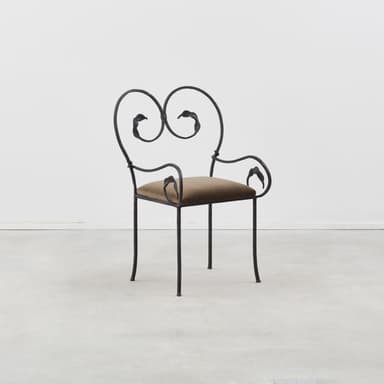 An ornate accent chair featuring a black wrought iron frame with scrolling details and a small, padded brown upholstered seat. The backrest forms a heart-like shape with stylized leaf motifs, echoed on the integrated armrests. The legs are slender and slightly curved, with small feet. — 3D model