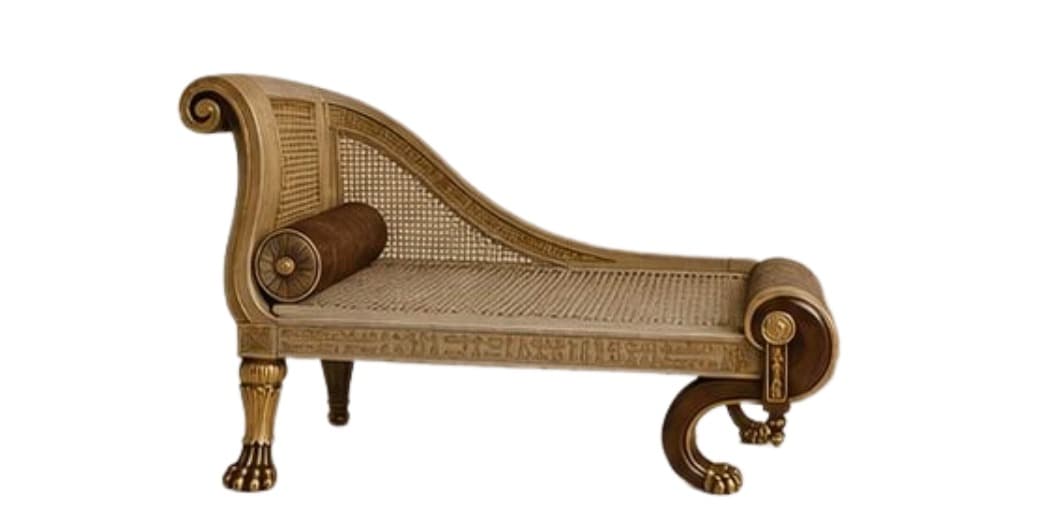 An Egyptian Revival chaise lounge featuring a carved wooden frame, caned seat and backrest, and elaborate decorative elements. The frame is primarily a light wood tone with gold-finished accents, including hieroglyphic carvings along the skirt and lion paw feet at the front. The armrests are dramatically scrolled, with a higher, upright scroll at one end and a lower, inward-curving scroll at the other. A cylindrical bolster pillow in a dark brown fabric is positioned at the higher armrest. — 3D model