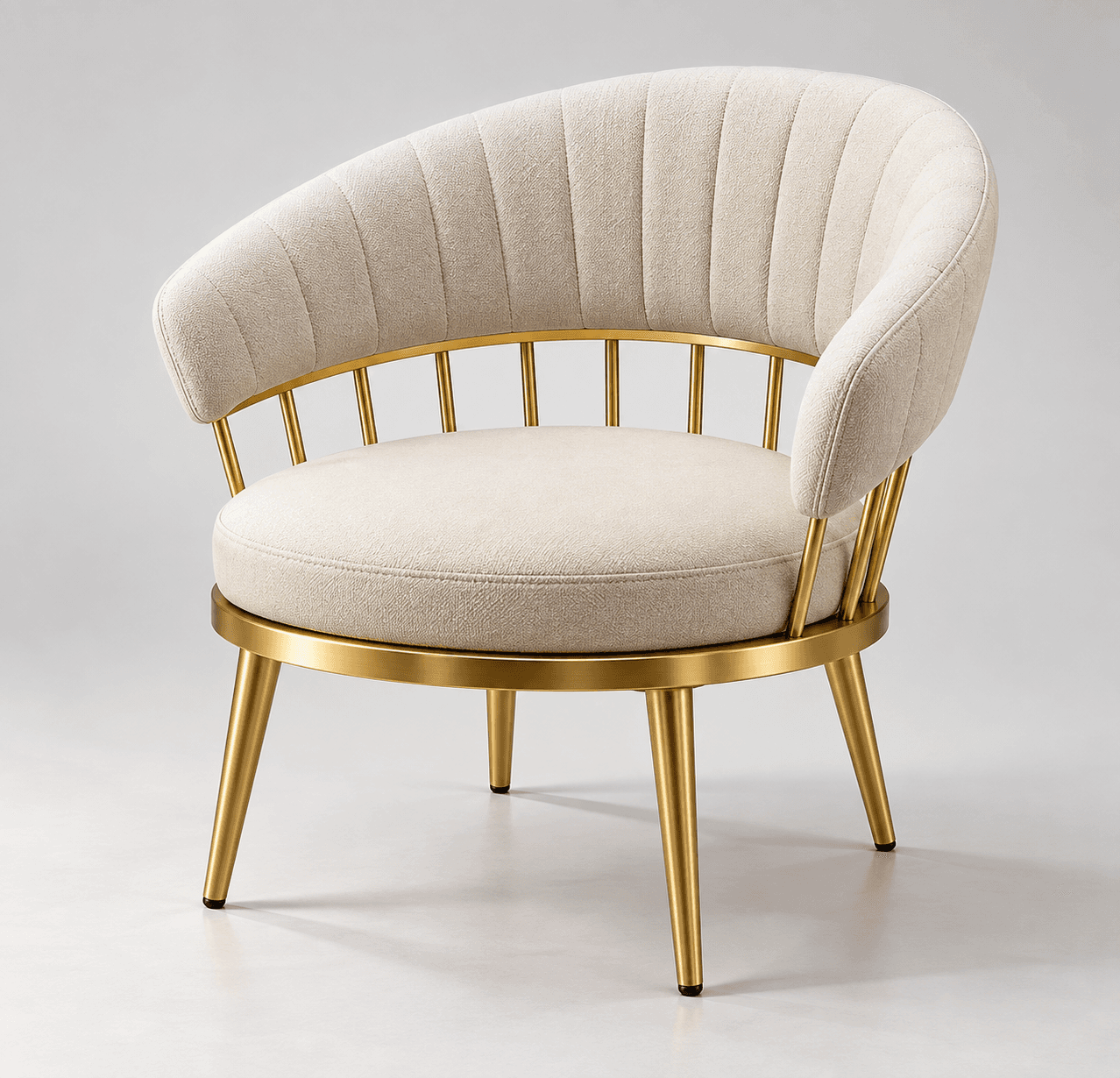 An elegant armchair featuring a rounded, barrel-shaped backrest with integrated arms, upholstered in a light beige fabric with vertical channel tufting. The circular seat cushion is also upholstered in the same fabric. The chair is supported by a polished gold-finished metal frame that forms the base and extends into four slender, tapered legs. — 3D model