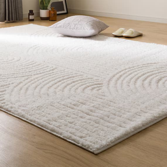 A rectangular rug with a textured surface and a subtle abstract pattern composed of curved lines and parallel strokes. The rug appears to be made of a soft, plush material. It is placed on a wooden floor. — 3D model